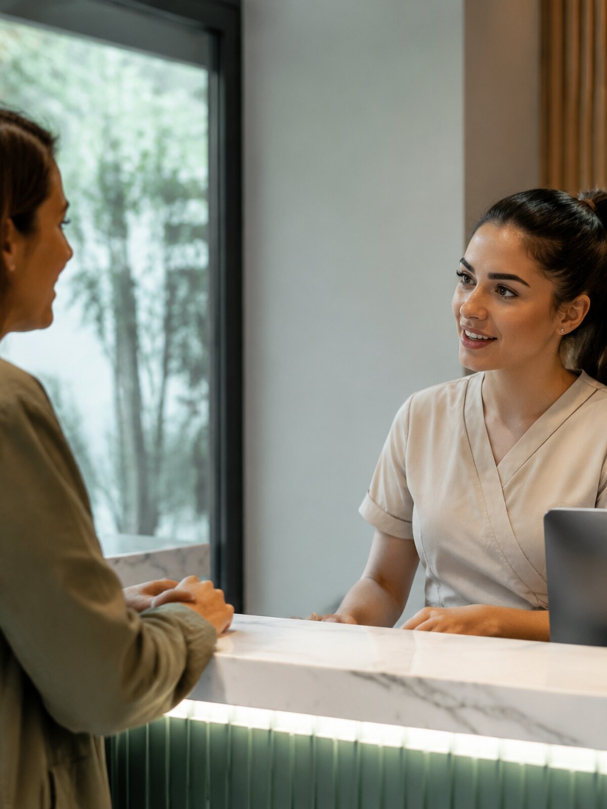 Paciente hablando con la recepcionista de una clínica moderna
